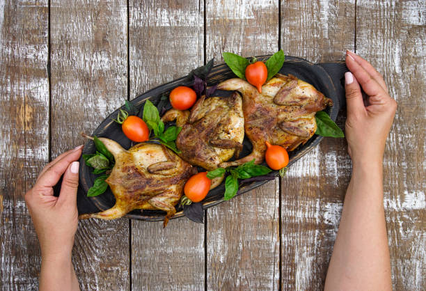Women's hands hold a dish with grilled quails