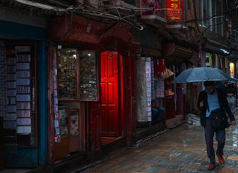 Kathmandu, Nepal - August 04, 2022: Street with shops and red door during rainy season.