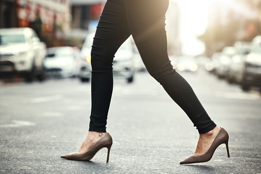 High heels, business and woman crossing the street closeup in a city on her commute to work. Feet, fashion and a female employee walking on an asphalt road in an urban town for a professional career