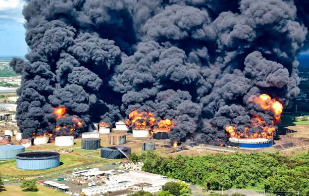 A fire is burning at the oil depot, and a lot of black smoke rises into the sky.