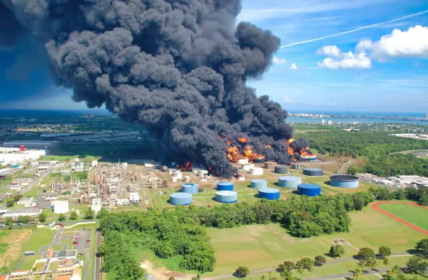 A fire is burning at the oil depot, and a lot of black smoke rises into the sky.