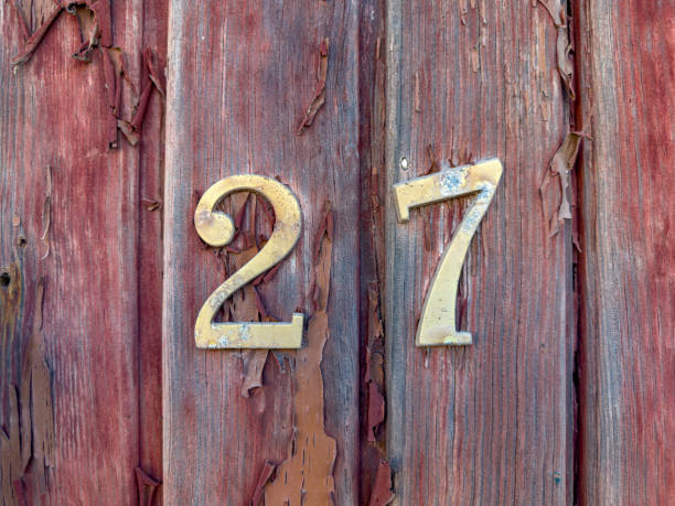istock Number 27 on red painted old wooden wall. 1613893723