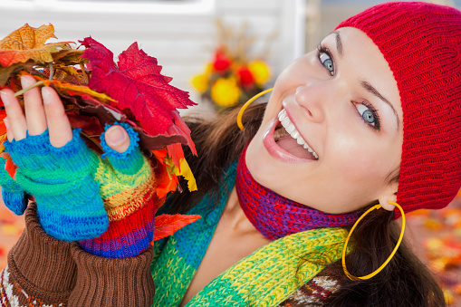 Laughing beautiful Ukrainian woman holding a handful of autumn maple leaves.