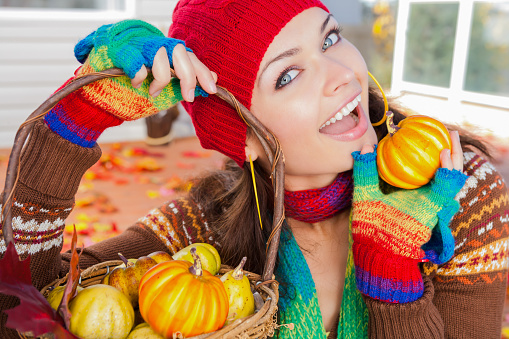Smiling beautiful Ukrainian woman holding basket of pumpkins