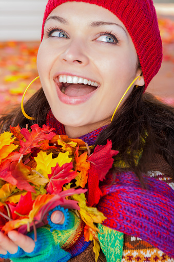 Laughing beautiful Ukrainian woman holding a handful of autumn maple leaves.