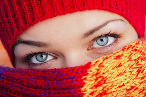 Beautiful Ukrainian woman covering face with colourful scarf.