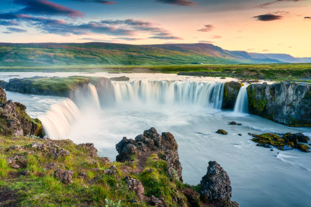 Godafoss waterfall flowing with colorful sunset sky in summer at Iceland Majestic landscape of Godafoss waterfall or waterfall of the gods flowing and colorful sunset sky on Skjalfandafljot river in summer at Northern Iceland akureyri stock pictures, royalty-free photos & images