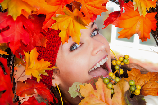 Smiling beautiful Ukrainian woman looking through an autumn wreath.