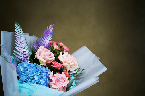 Beautiful colorful mixed flower bouquet. Man hands holding flowers bouquet, dark background, copy space, close-up