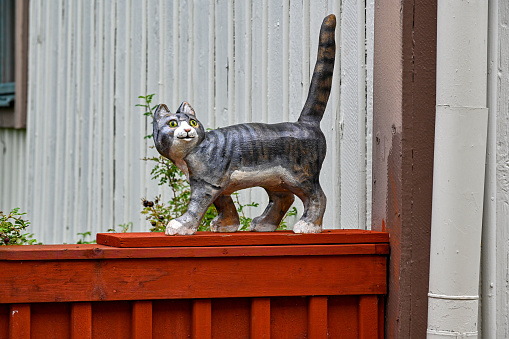 artificial cat walking on red wooden fence Wadkoping Orebro Sweden august 9 2023 with tail standig up