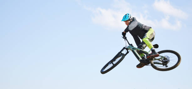 mountainbike, mann und sprung in blauem himmel für wettbewerb, freiheit oder abenteuer auf mockup-space. banner des athleten, des sports und des fahrrads in der luft für action, cardio-rennen und mut zum stunt, zur geschwindigkeit oder zum risiko - endurance sport stock-fotos und bilder