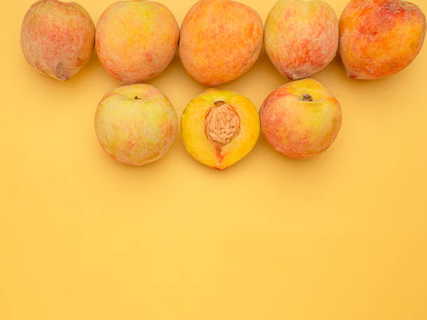 Pile of fresh peaches fruit over a yellow background