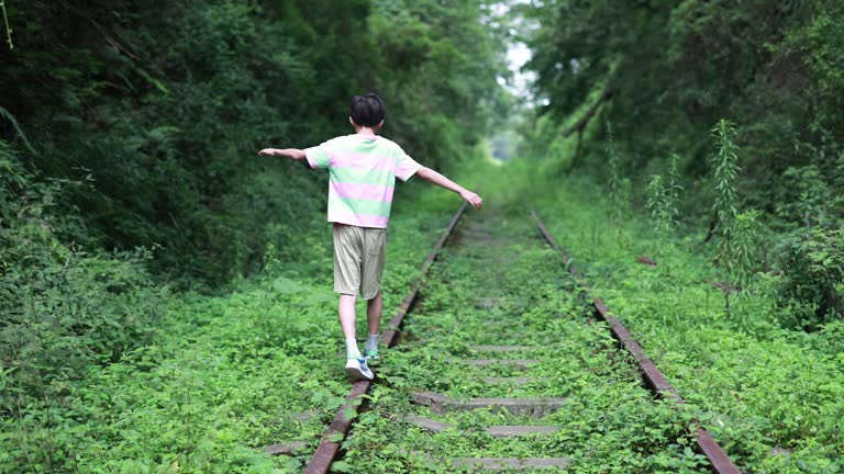 Boy walking on railroad track