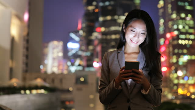 Business woman looking at cellphone in Hong Kong at night