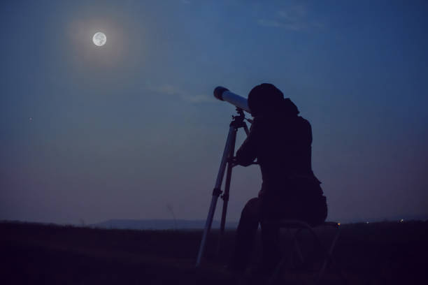 istock Girl looking at the moon through a telescope 1614002527