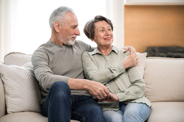 istock elderly couple sitting on couch and watching TV 1614009100