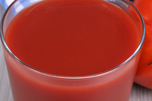 Glass of fresh tomato juice close up on background