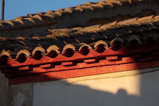 Detail of the rows of tiles forming the roof and eaves of a house, illuminated by sunset light, in a village in rural Spain