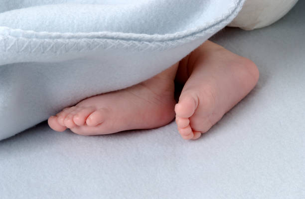 istock Small, newborn baby feet close up under a blanket 1614018917
