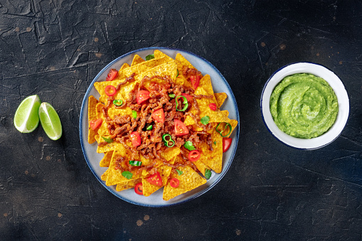 Mexican tomato salsa dip sauce with Nacho chips and chili on a rustic wooden table with copy space
