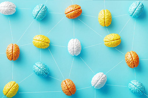 Colorful brain objects connected by dotted lines on blue background. Horizontal composition with copy space. AI and deep learning concept.