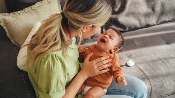 Young mother tries to calm her screaming newborn baby stock photo