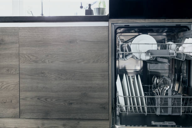 istock Front view of built-in opened dishwasher machine at kitchen with clean utensil 1614059303