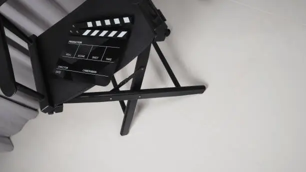 Photo of Clapper board or movie slate with black director chair use in video production , movie, cinema industry.