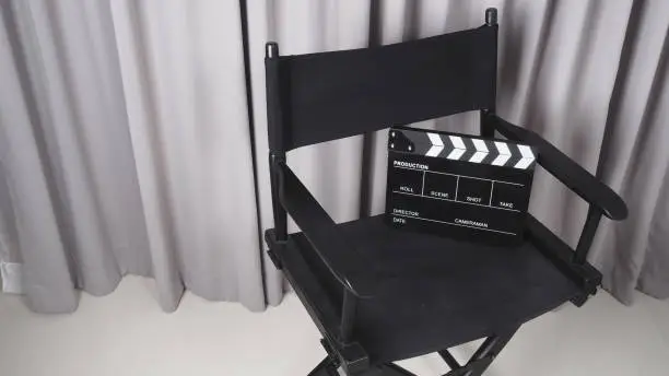 Photo of Clapper board or movie slate with black director chair use in video production , movie, cinema industry.