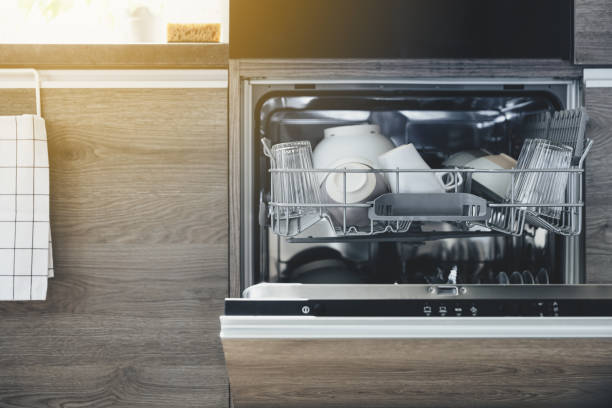 istock Front view of built-in opened dishwasher machine at kitchen with clean utensil 1614060952