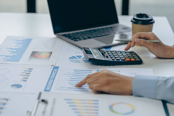 istock Female accountant analyzing charts, graphs, computer, investment tablet and pressing calculator button above document. Accountants, accountants, clerks, bank consultants and auditors. close-up photo 1614076465