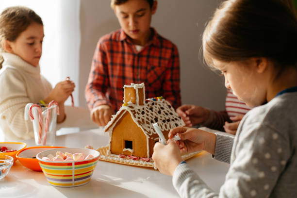 istock Children having fun decorating Gingerbread house 1614079226