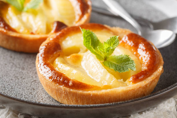Classic baked Apple tartlet with custard and mint closeup in a plate on the table. Horizontal