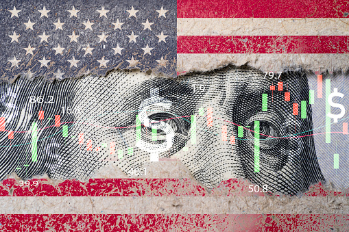 Closeup Benjamin Franklin face on USD banknote with stock market chart graph and United States flag for currency exchange and global trade forex concept.