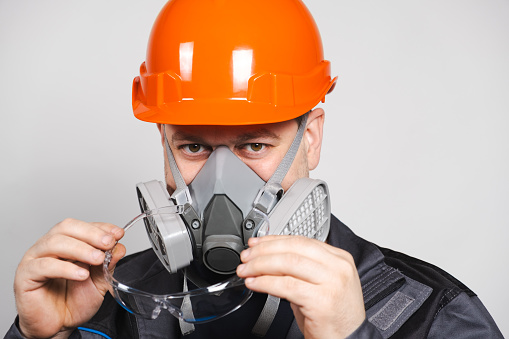 A man wearing a helmet, respirator and goggles on a white background.