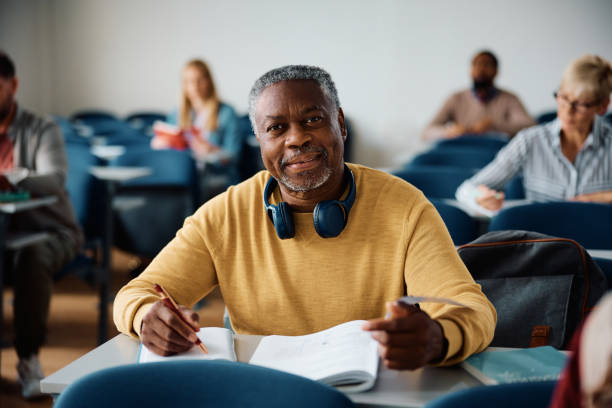 istock Smiling black mature man studying while attending adult education training class and looking at camera. 1614141406
