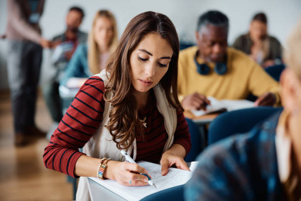 istock Young woman learning while attending adult education training class in lecture hall 1614142981