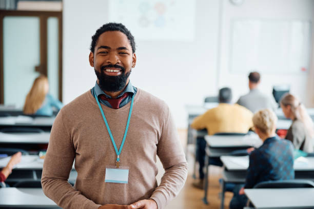 istock Happy black professor during a class with adult students in the classroom looking at camera. 1614143512
