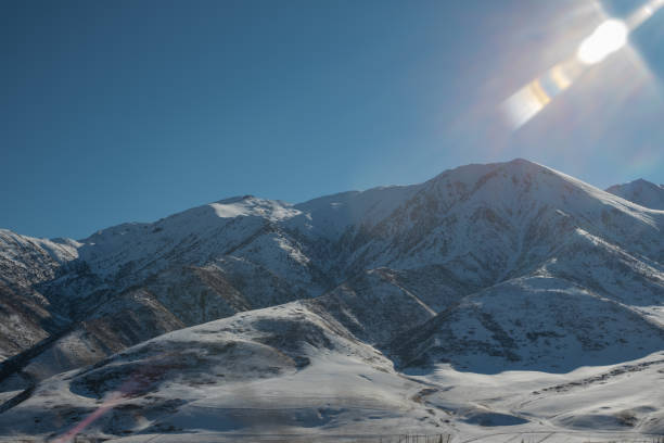 панорамный вид на заснеженные горы, освещенные солнцем. зима. красивое чистое голубое небо при дневном свете. впечатляющий вид на горные ве� - kazakhstan glacier snow mountain view стоковые фото и изображения