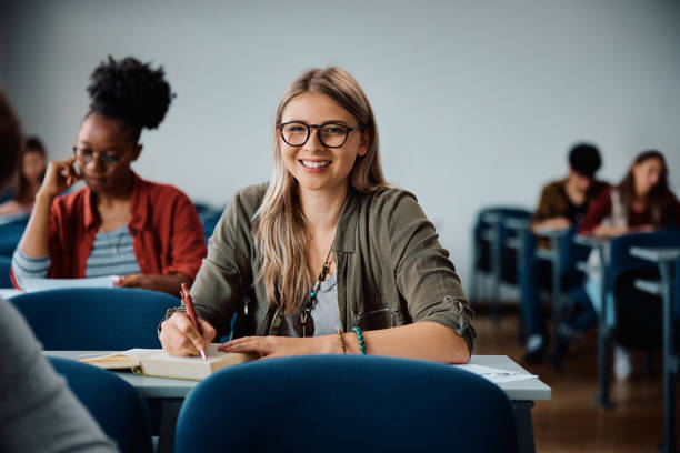 istock Happy female college student during a class in lecture hall looking at camera. 1614145709