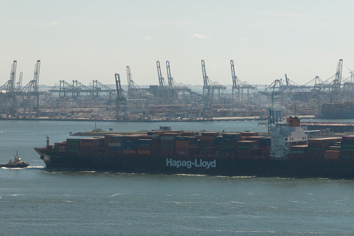 Container ship TSINGTAO EXPRESS of Hapag-Lloyd sailing in the port of Rotterdam seen from above. The Port of Rotterdam is the largest seaport in Europe, with several container terminals on the Maasvlakte.