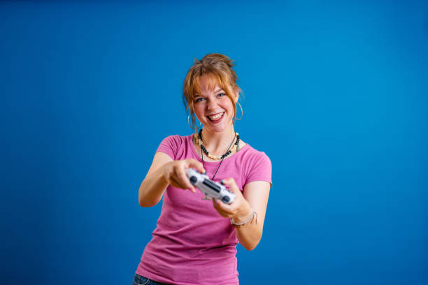 istock Young Woman Playing A Video Game Against A Blue Background 1614169636
