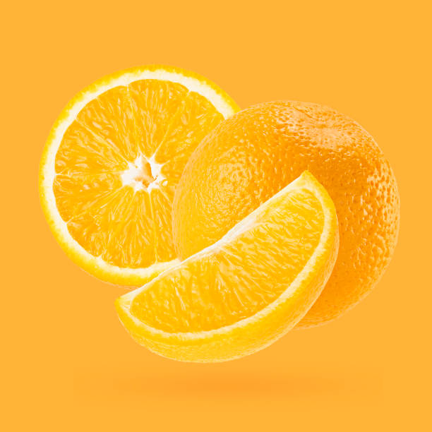 istock Juicy oranges closeup fly on white background as art composition. Whole, half and quarter piece fruits on pastel orange background with shadow. Summer fruits for advertising, design, label product. 1614188864