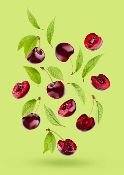 istock Juicy red cherry with green leaves as flow fly or fall as art composition. Whole, half pieces fruits on bright green background with shadow. Ripe raw fruits for advertising, design, label product. 1614189847