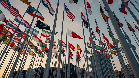 A low angle of international flags blowing in the wind at sunset in Doha, Qatar