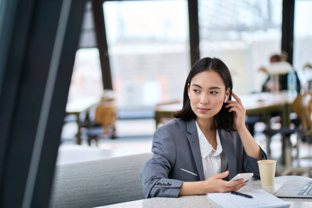 istock Young Asian business woman using smartphone working in modern office. 1614211049