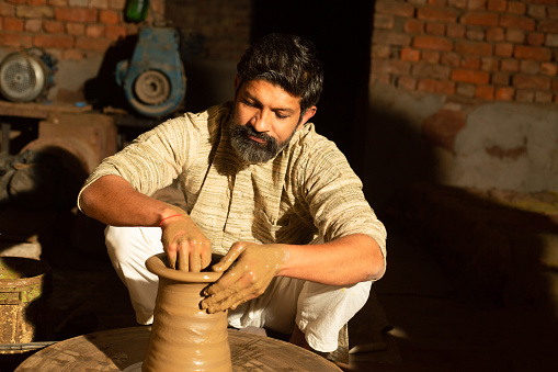 Indian male pottery maker building a clay pot, Beard man worker or labour working.skill india concept.