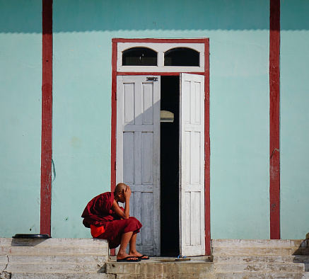 Nyaungshwe, Myanmar - Feb 14, 2016. A novice sitting at main door of monastery in Nyaungshwe, Myanmar. Nyaungshwe is a township of Taunggyi in the Shan State of Myanmar.