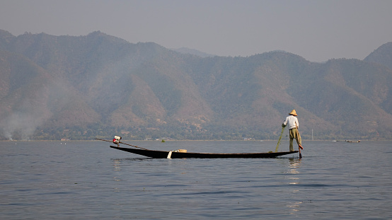 Inle, Myanmar - Feb 15, 2016. Burmese man rowing boat on Inle lake in Myanmar. Inle is the second largest lake in Myanmar with an estimated surface area of 44.9 square miles.