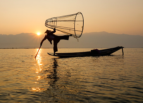 Inle, Myanmar - Feb 16, 2016. A man catching fish on Inle lake in Myanmar. Inle is the second largest lake in Myanmar with an estimated surface area of 44.9 square miles.